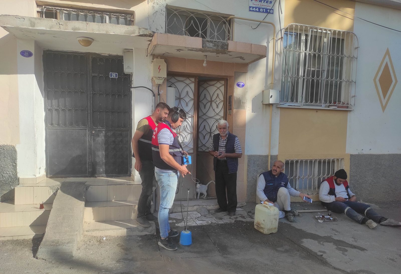 LeakExpert ekibinden bir kişi gündüz bir sokakta yer mikrofonu ve dinleme cihazıyla akustik tarama yaparken